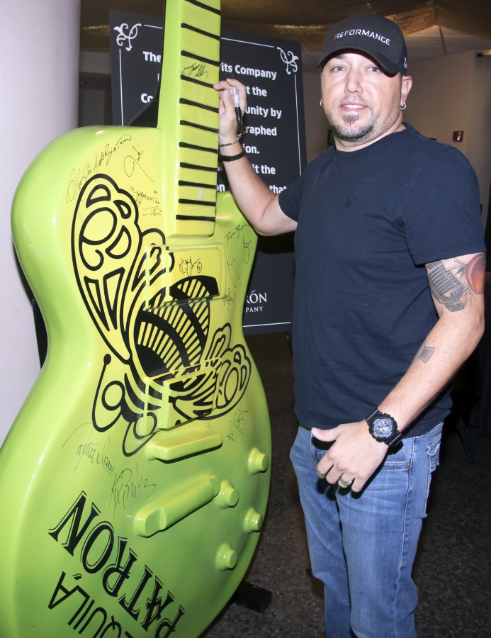 Jason Aldean signs a giant Patrón tequila guitar backstage at the CMA Awards Tuesday November 3, 2015.