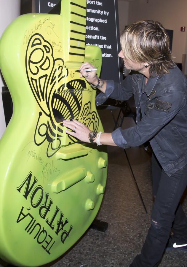 Keith Urban signs a giant Patrón tequila guitar backstage at the CMA Awards Tuesday November 3, 2015.
